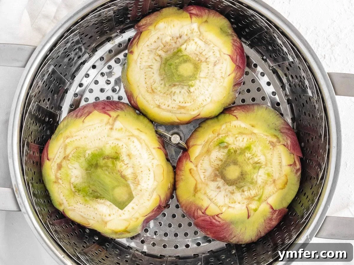 Three prepped artichokes neatly arranged in a steamer basket, ready for cooking.