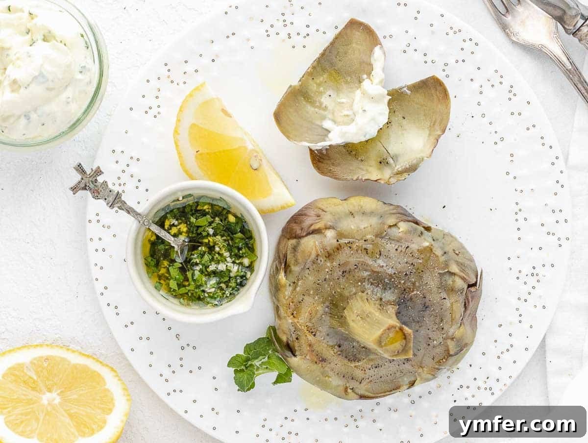 A steamed artichoke leaf being dipped into creamy mayonnaise, demonstrating the traditional way of eating.