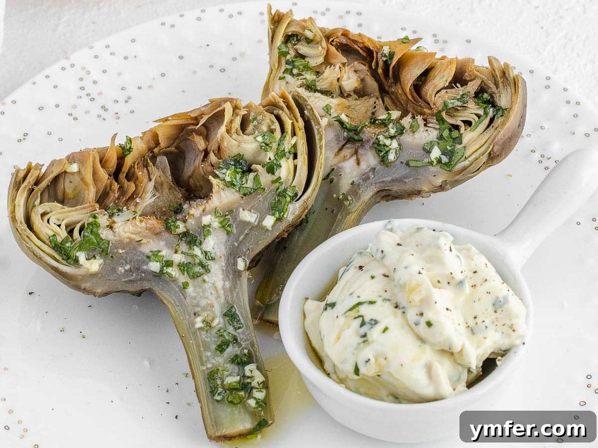 Halved steamed artichokes garnished with a vibrant salsa verde, ready to be served.