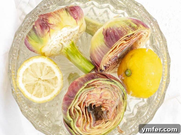 Cleaned artichokes immersed in a bowl of cold lemon water to preserve their fresh color.