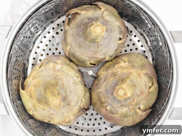 Artichokes steaming in a basket, with a knife inserted to check for tenderness, indicating doneness.