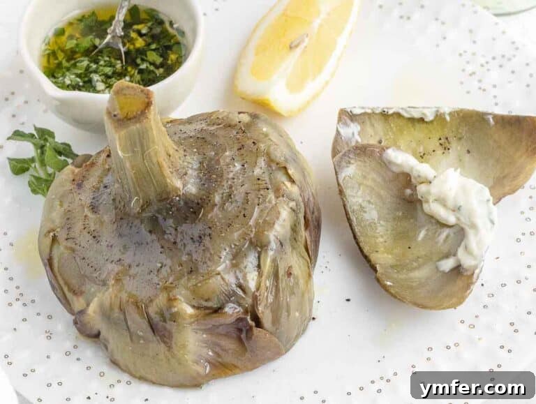 A beautifully presented steamed artichoke served with creamy vegan mayonnaise on a plate.