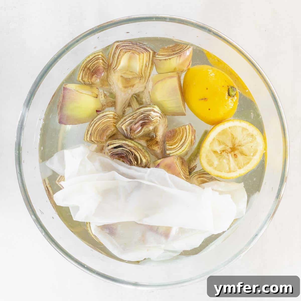 Artichokes soaking in lemon water to prevent browning