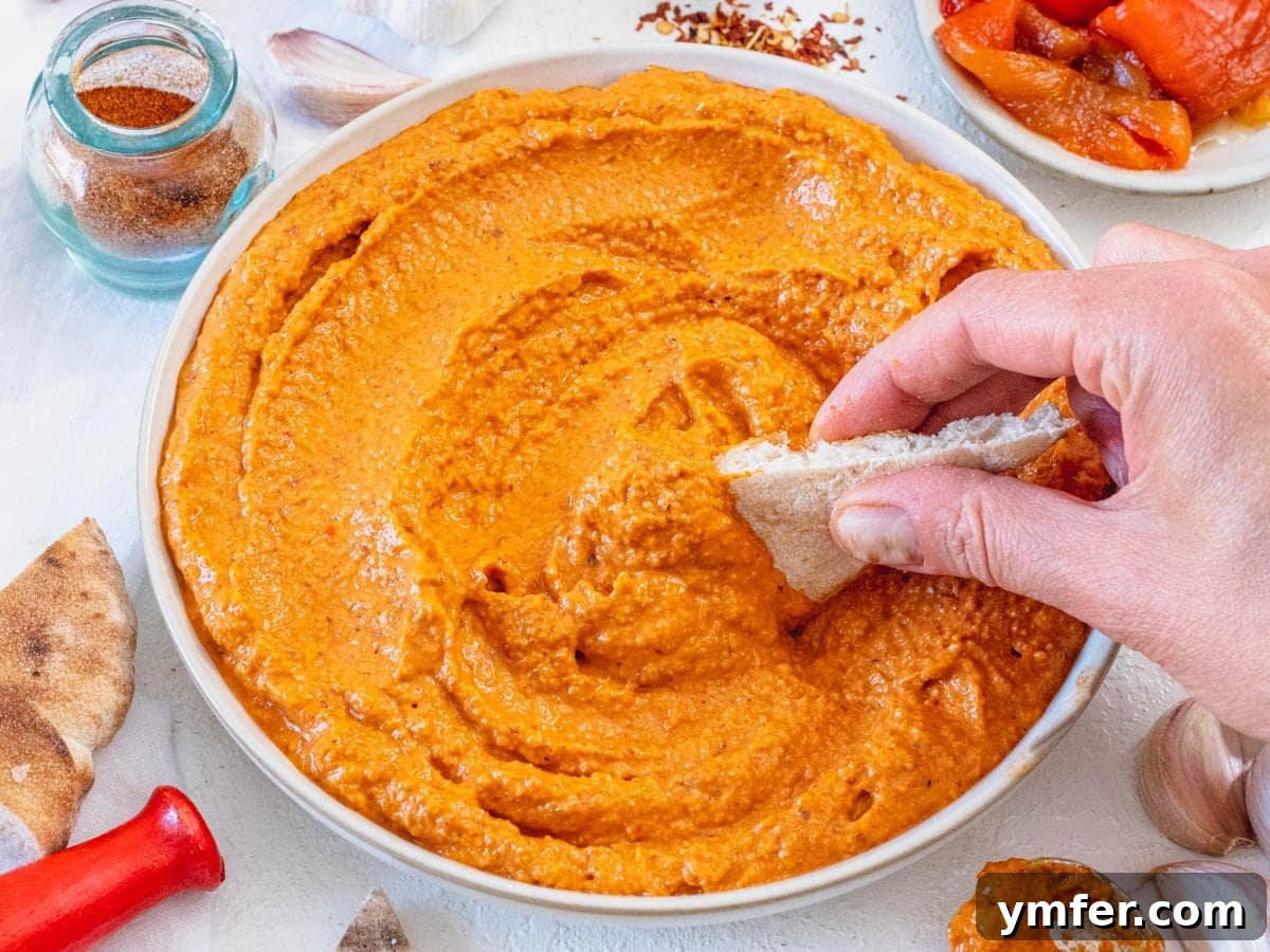 30 Crowd-Pleasing Vegan Starters 4 Rich Romesco sauce served as a dip, with a hand holding warm pita bread for dipping.