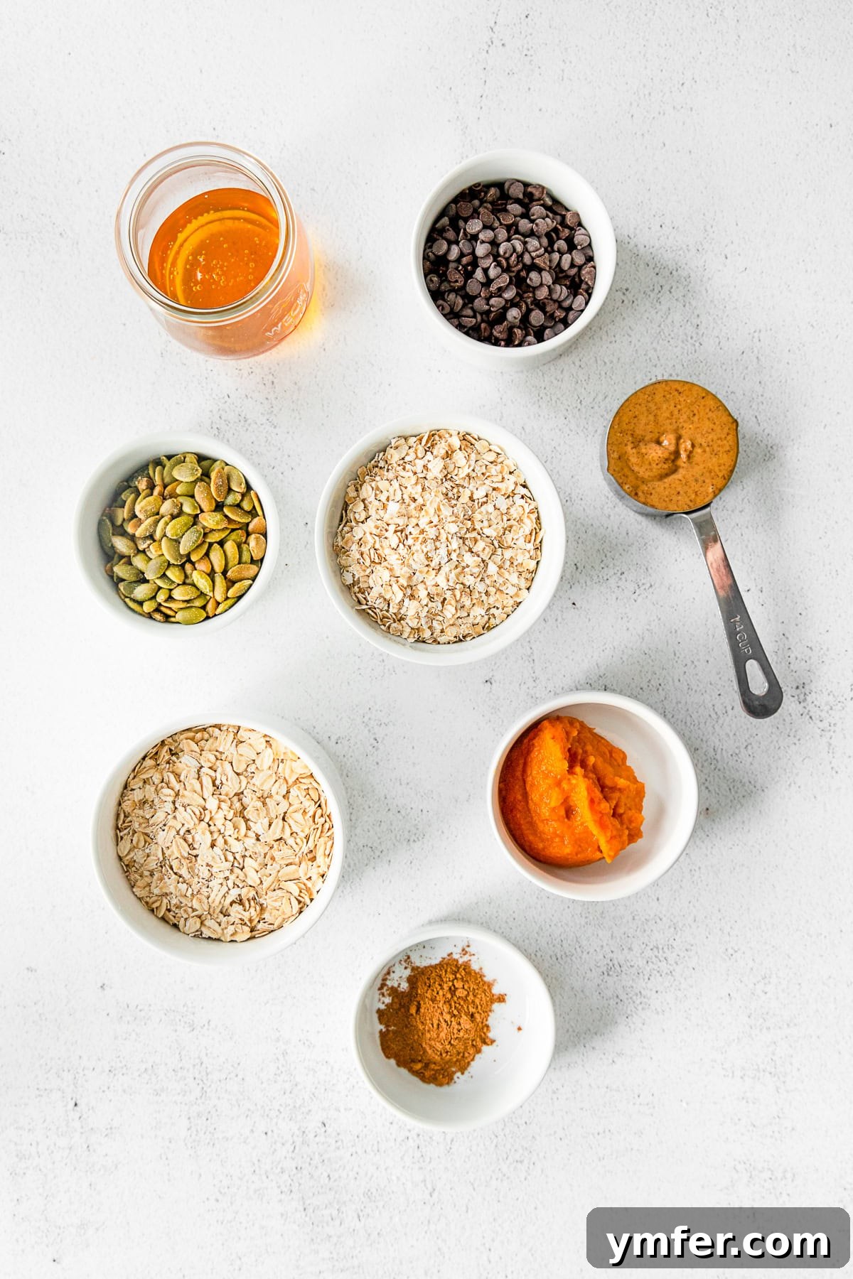 Ingredients for Pumpkin Energy Balls, including oats, peanut butter, pumpkin puree, spices, and chocolate chips, laid out on a table.