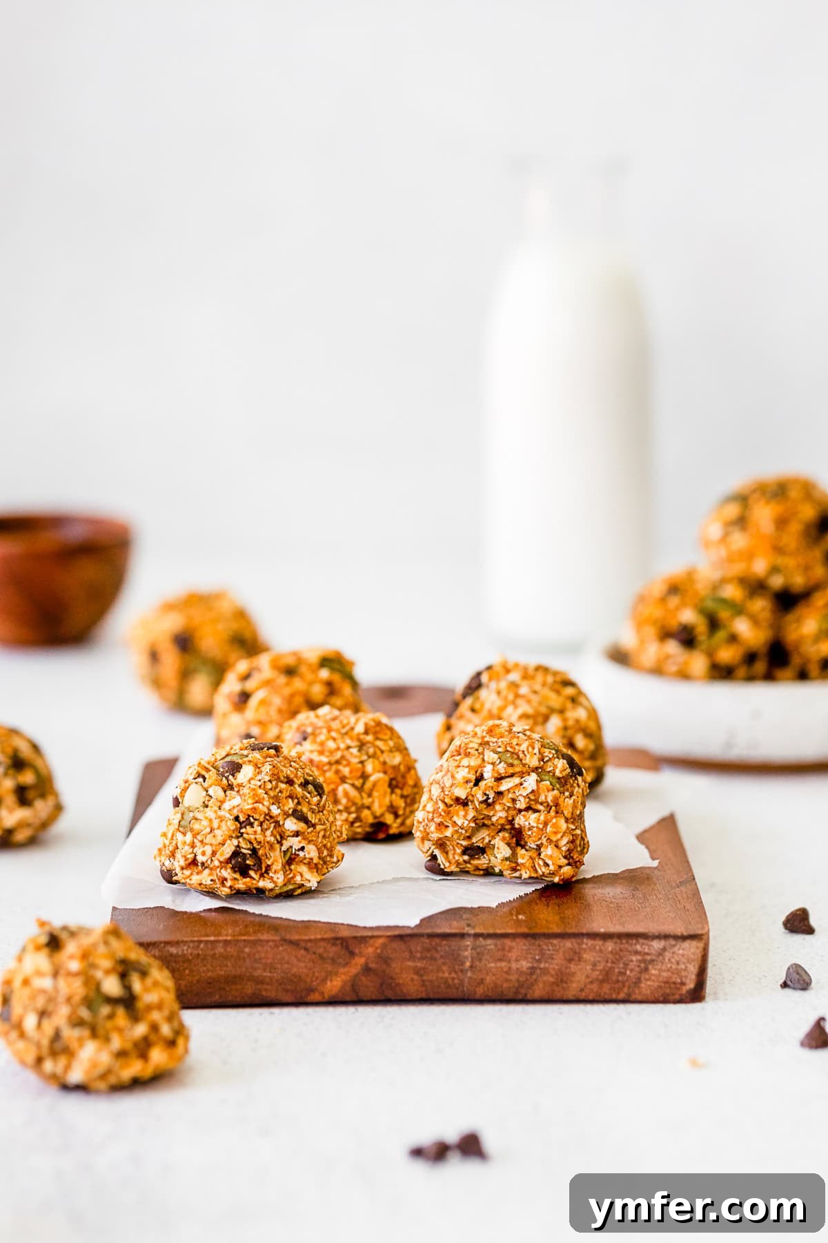 A pumpkin energy ball with a bite taken out, revealing the wholesome ingredients inside, on a wooden surface.