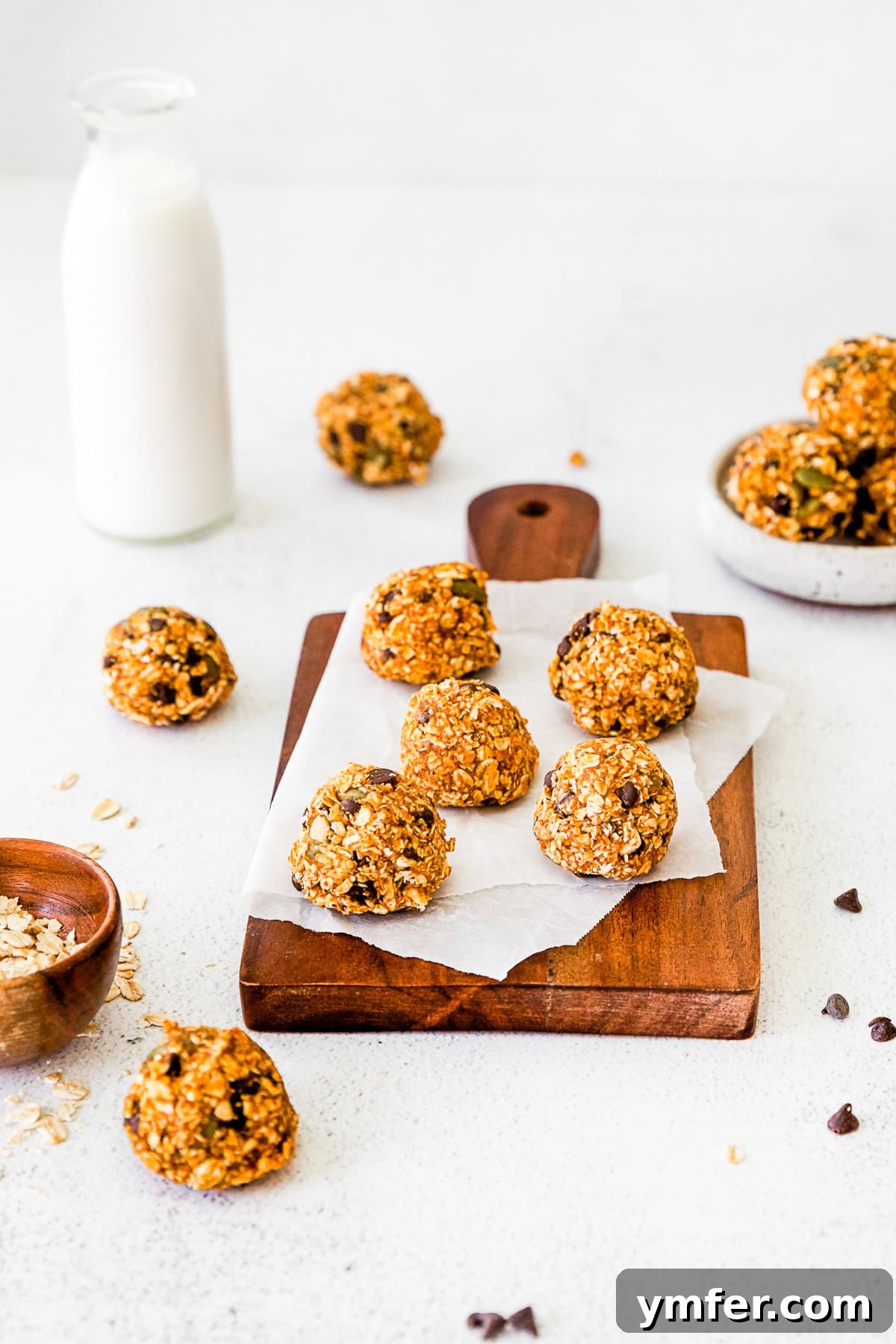 Pumpkin Energy Balls resting on parchment paper on a wooden cutting board, showcasing their appealing texture.