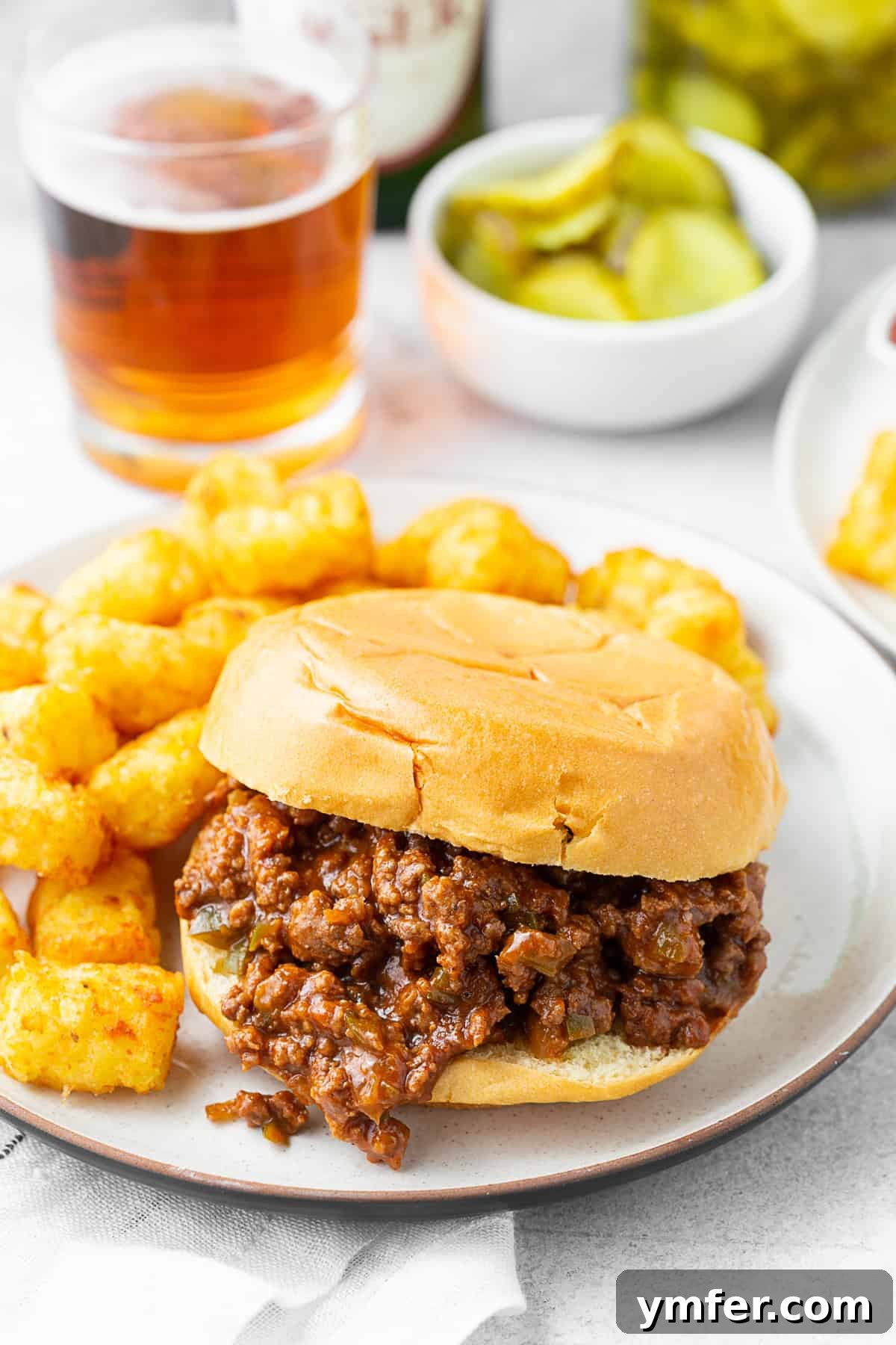 Irresistibly Messy Homemade Joes 2 Classic Homemade Sloppy Joes on a soft bun with a side of tater tots.