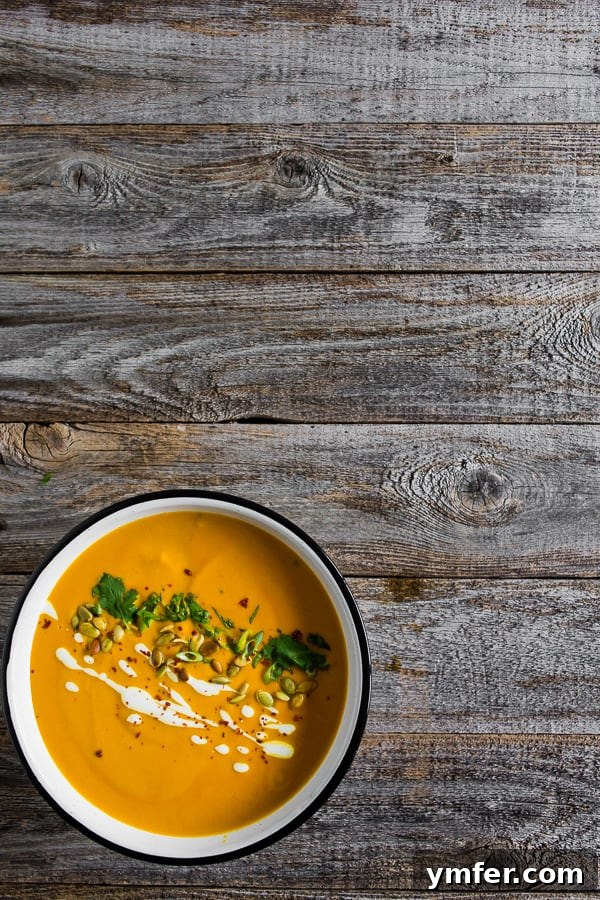 Thai Pumpkin Spice Soup 4 A bowl of Spicy Thai Pumpkin Soup sitting on a rustic wooden table.