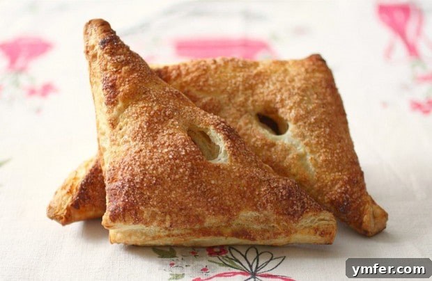 Golden brown pumpkin butter turnover, freshly baked and dusted with cinnamon sugar, on a baking sheet
