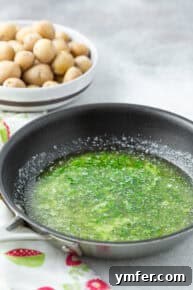 Melted butter infused with fresh herbs and black pepper in a skillet.