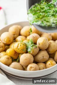 Herb butter being poured and tossed over the boiled salt potatoes.