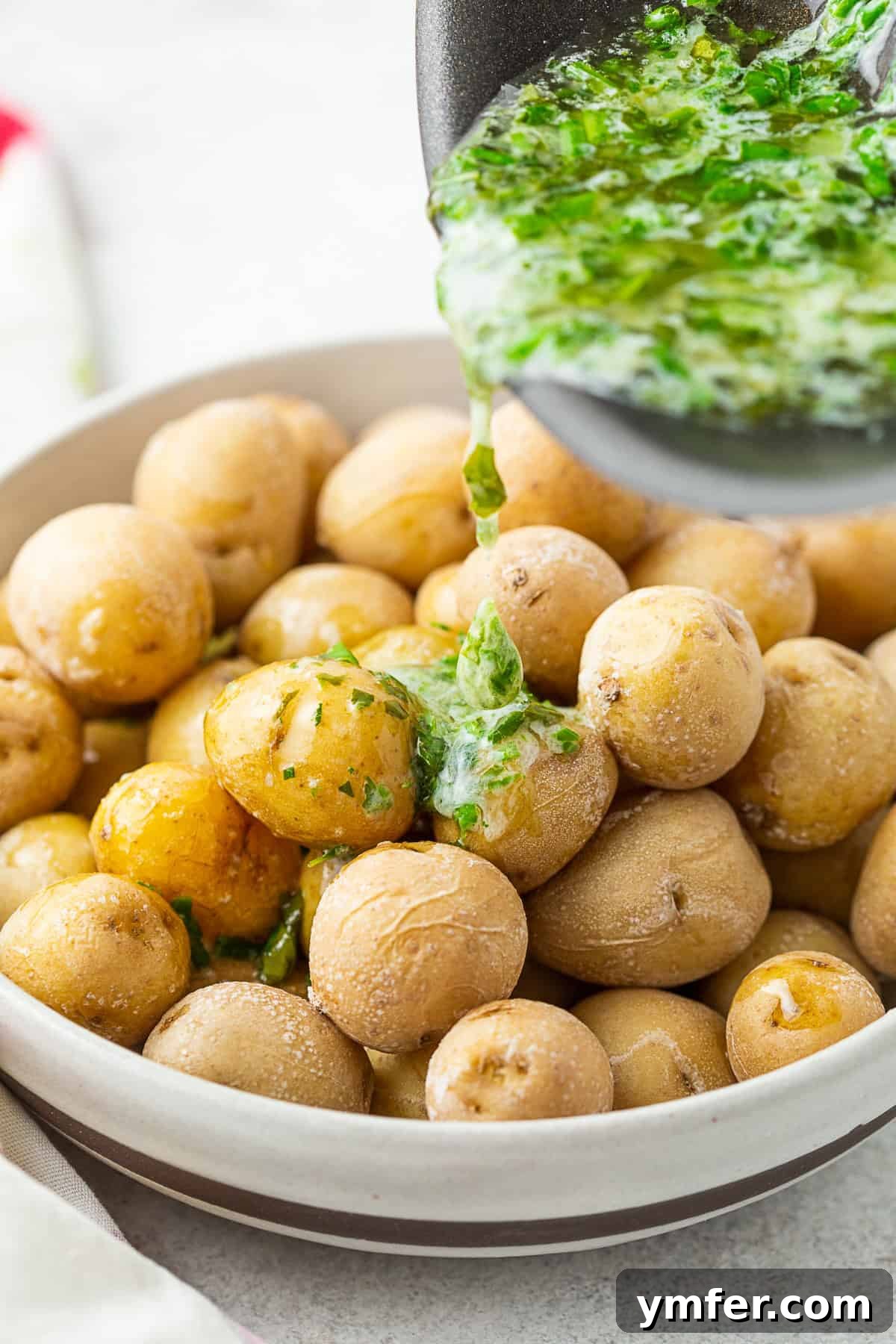 Pouring melted fresh herb butter over a bowl of hot Syracuse Salt Potatoes.