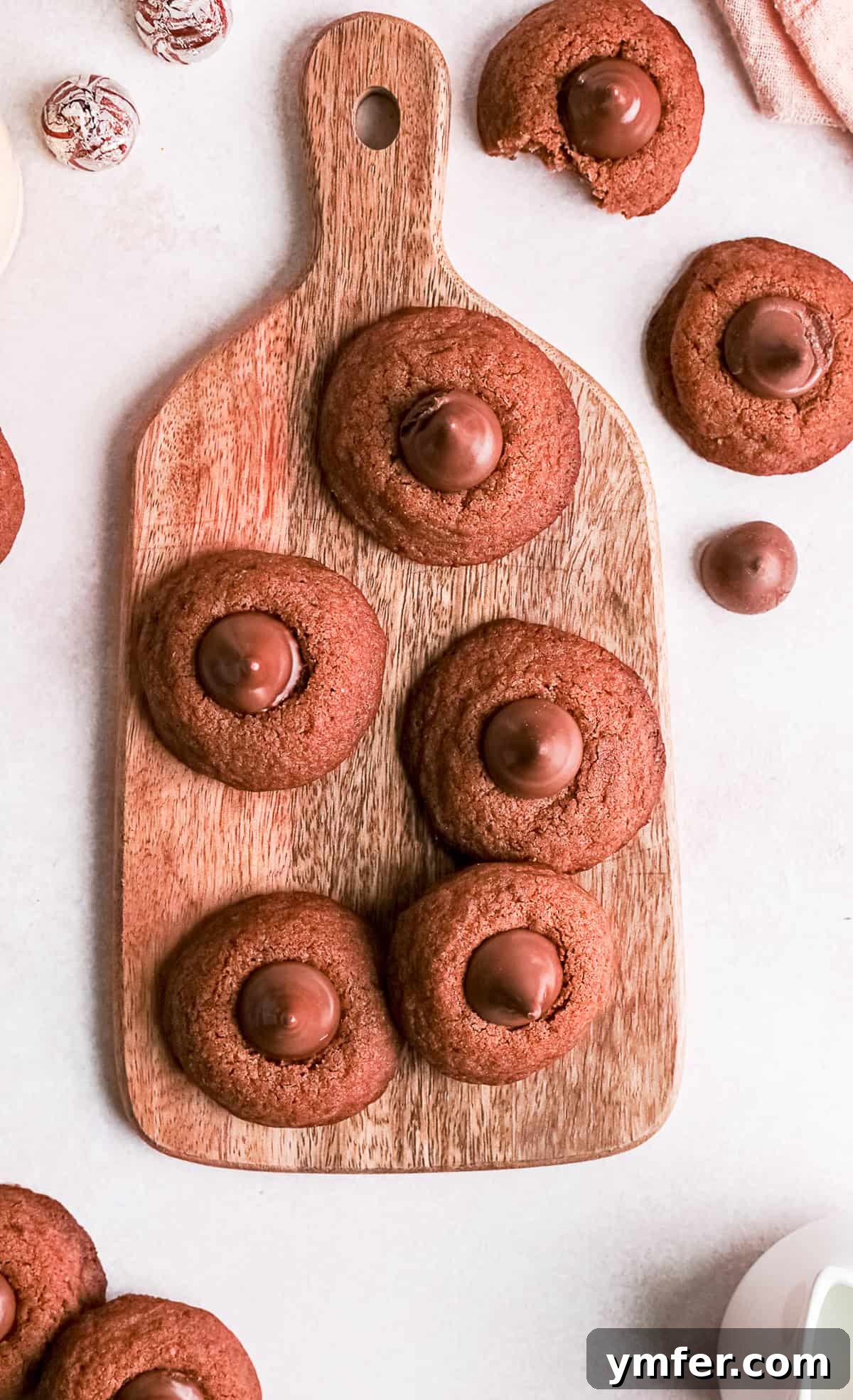 Chocolate Kissed Delights 2 Chocolate Blossom Cookies sitting on a wooden cutting board, showcasing their rich color and iconic Hershey's Kiss topping.