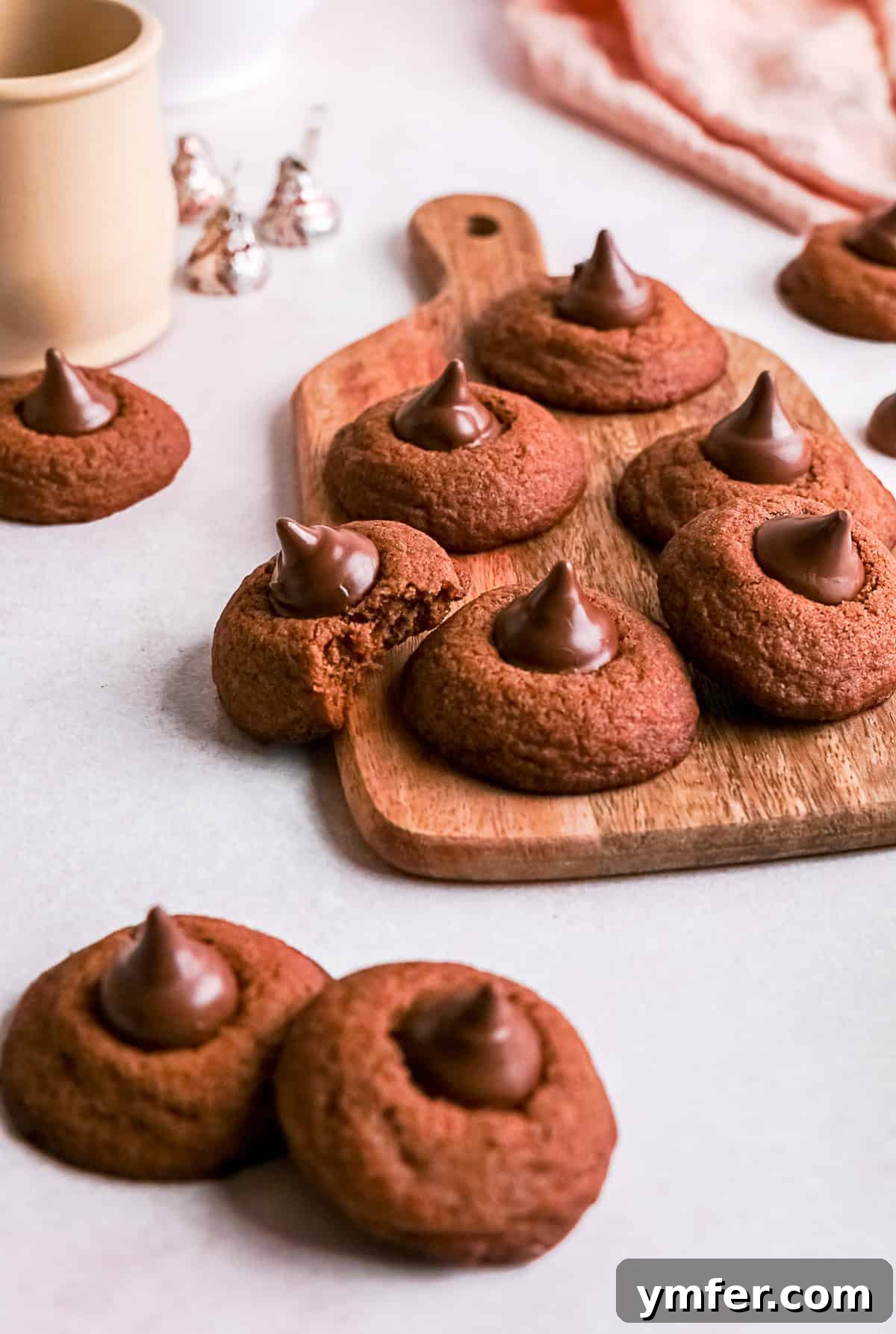 Chocolate Kissed Delights 4 Chocolate Blossom Cookies, with one having a bite taken out to reveal its soft, rich interior, arranged on a baking sheet.