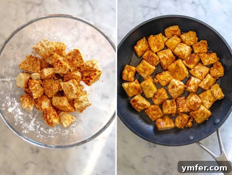 Fried tofu chunks in a skillet with olive oil and spices.