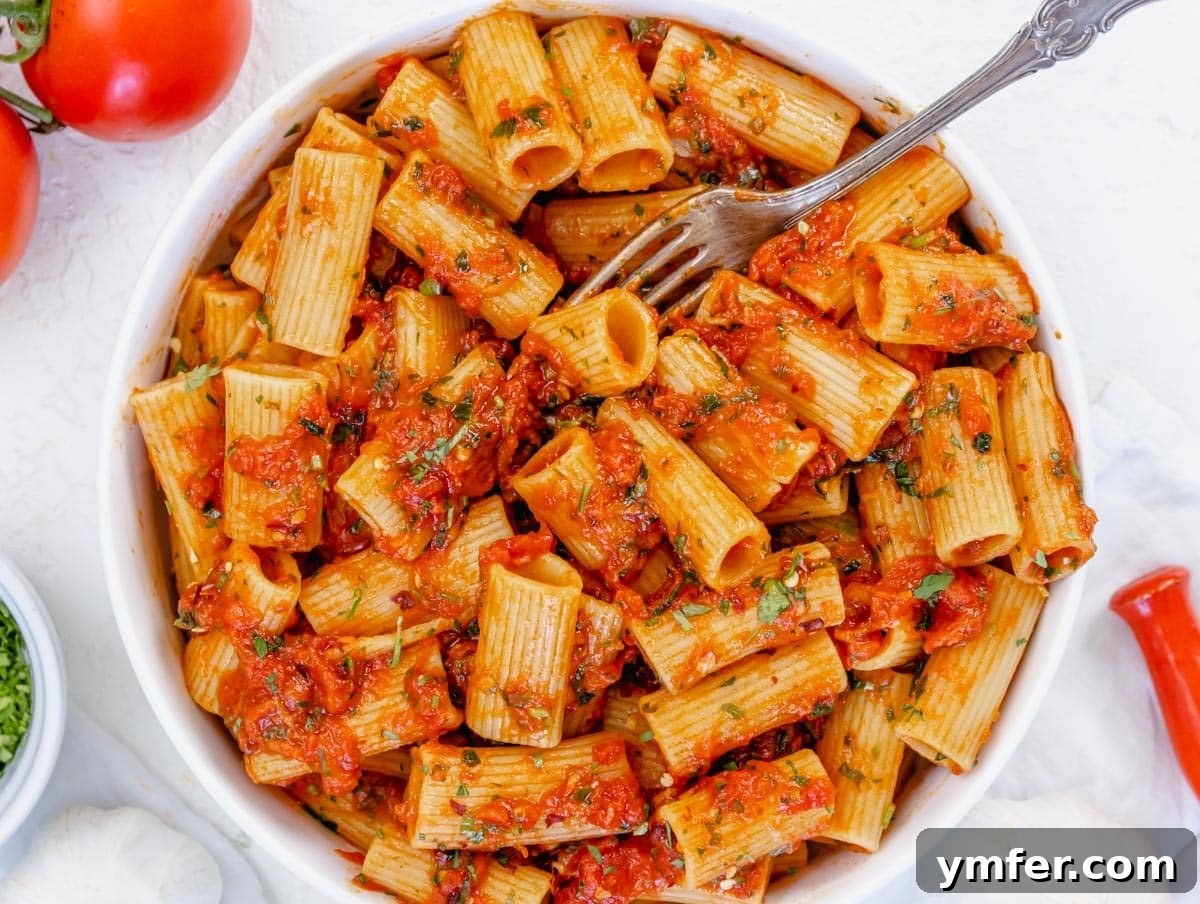 Fiery Rigatoni 3 rigatoni arrabbiata garnished with fresh parsley and a fork ready to serve