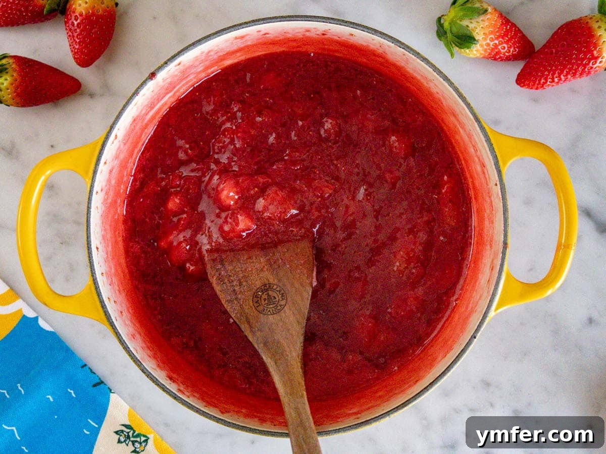 Summer in a Jar 8 Homemade strawberry jam in a saucepan, cooling down after cooking.