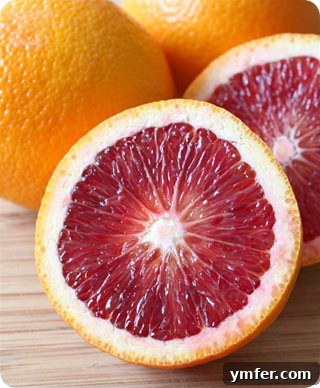Close-up of freshly cut blood oranges on a wooden board, showing their striking crimson and orange hues, ready to be juiced.