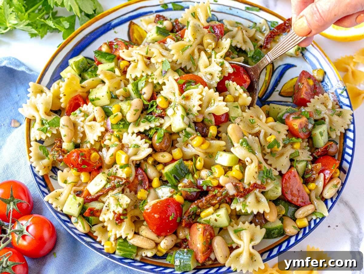Feast on Plants: 35 Vibrant Recipes 12 Vegan Pasta Salad garnished with fresh parsley, with a hand serving a portion.
