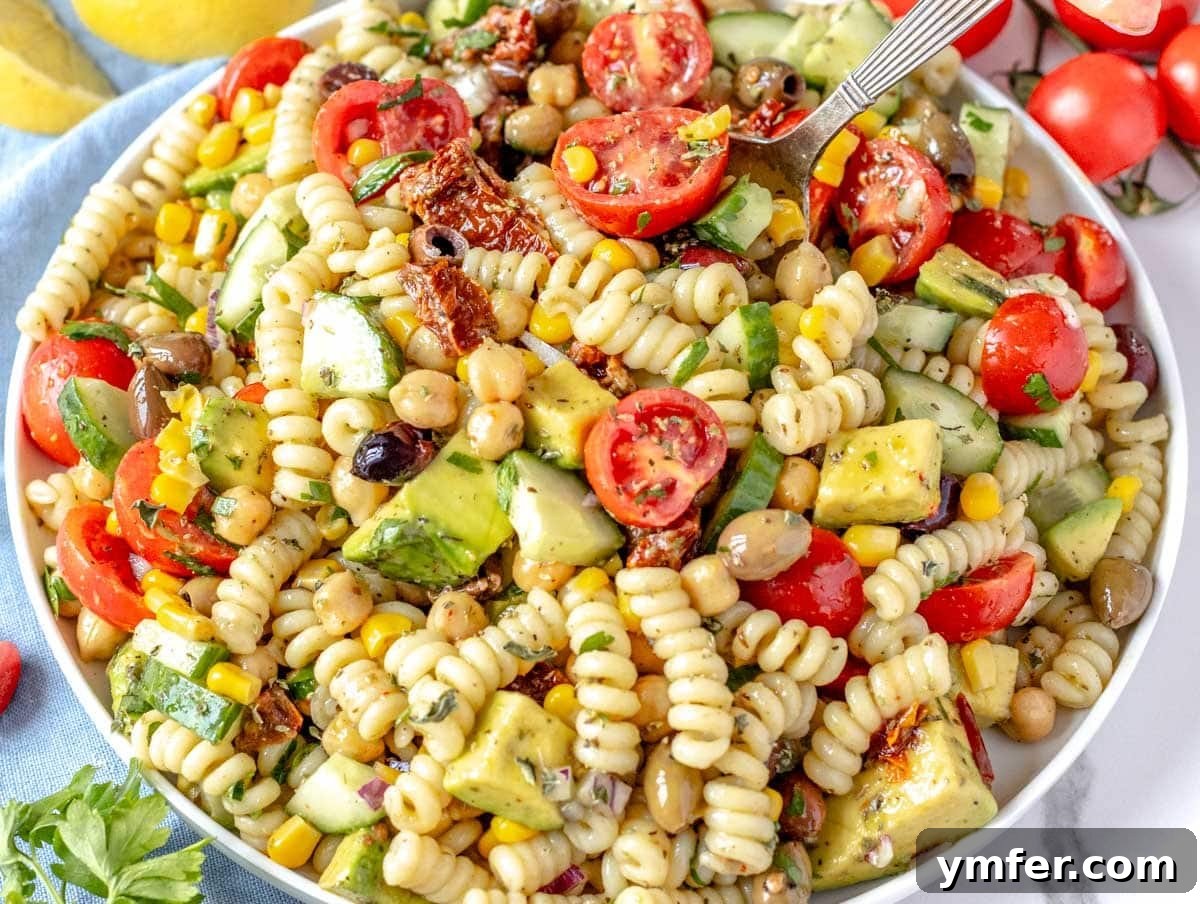 Feast on Plants: 35 Vibrant Recipes 14 Chickpea Pasta Salad served on a pristine white plate with an accompanying spoon.