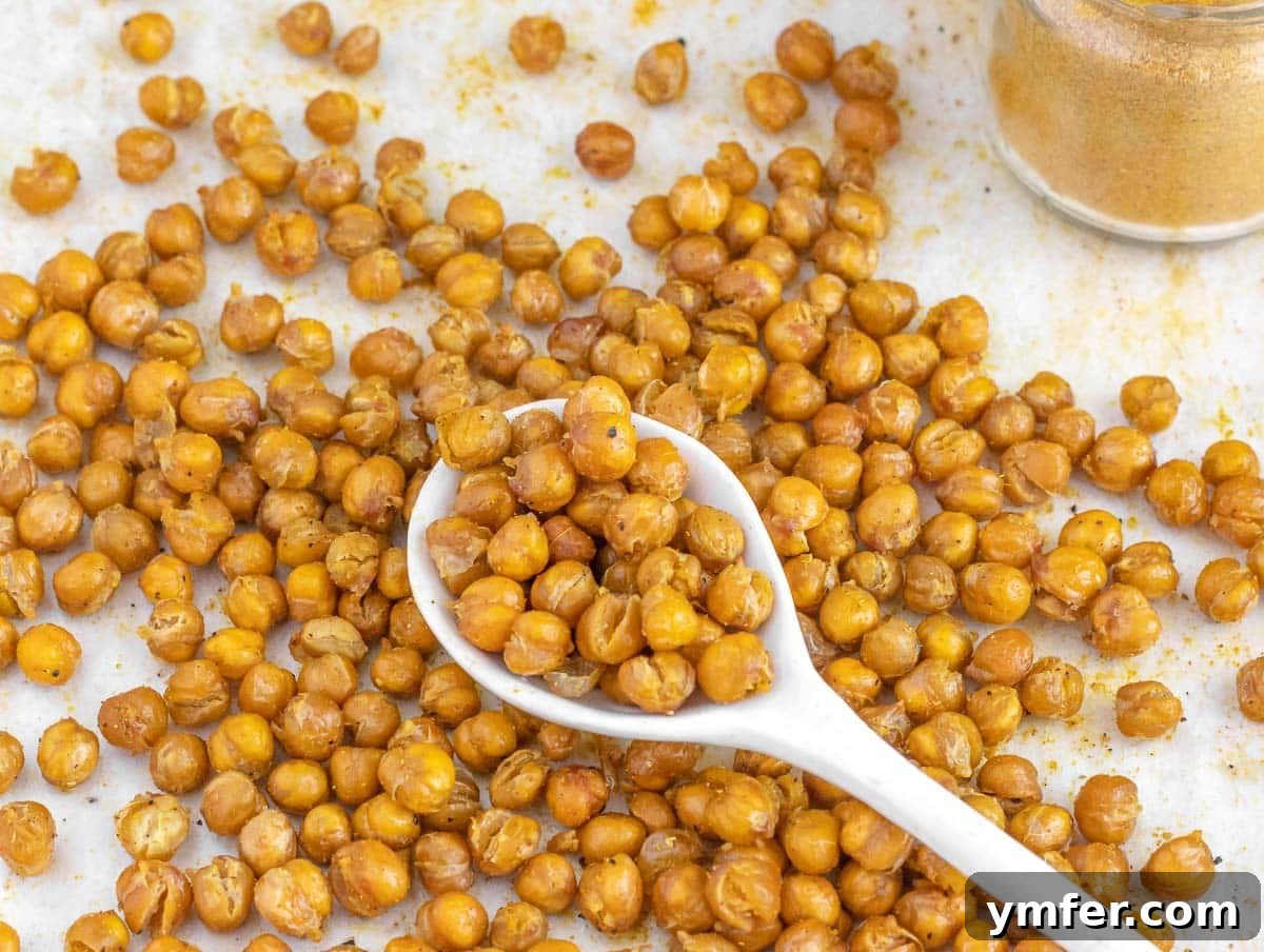35 Plant-Powered Chickpea Creations 3 Roasted chickpeas in a white bowl with a white spoon, ready to be enjoyed as a snack or meal topping.