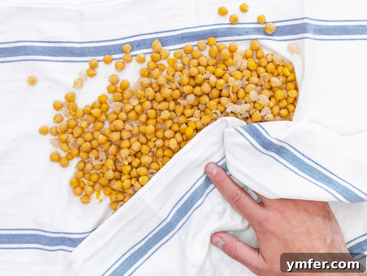 35 Plant-Powered Chickpea Creations 6 A hand gently removing skins from cooked chickpeas, a common step for extra smooth hummus.