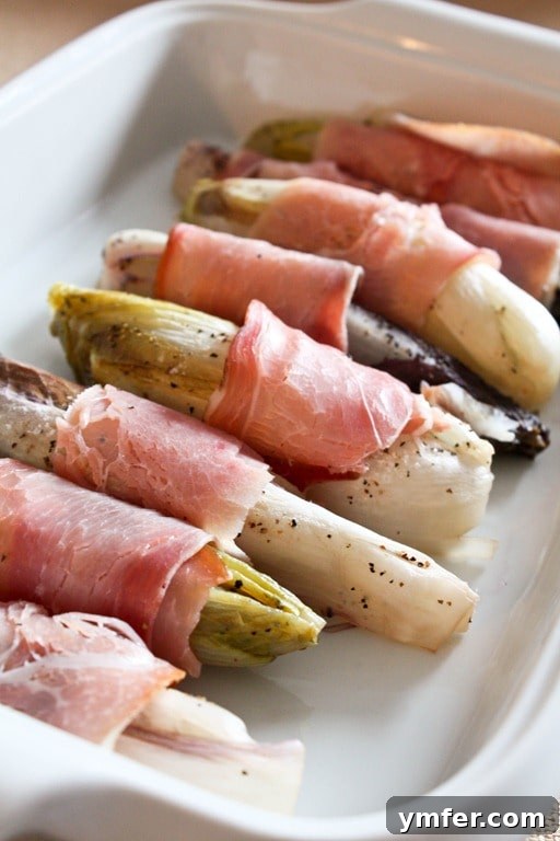 Fresh Belgian endives, halved and prepared for wrapping with prosciutto.