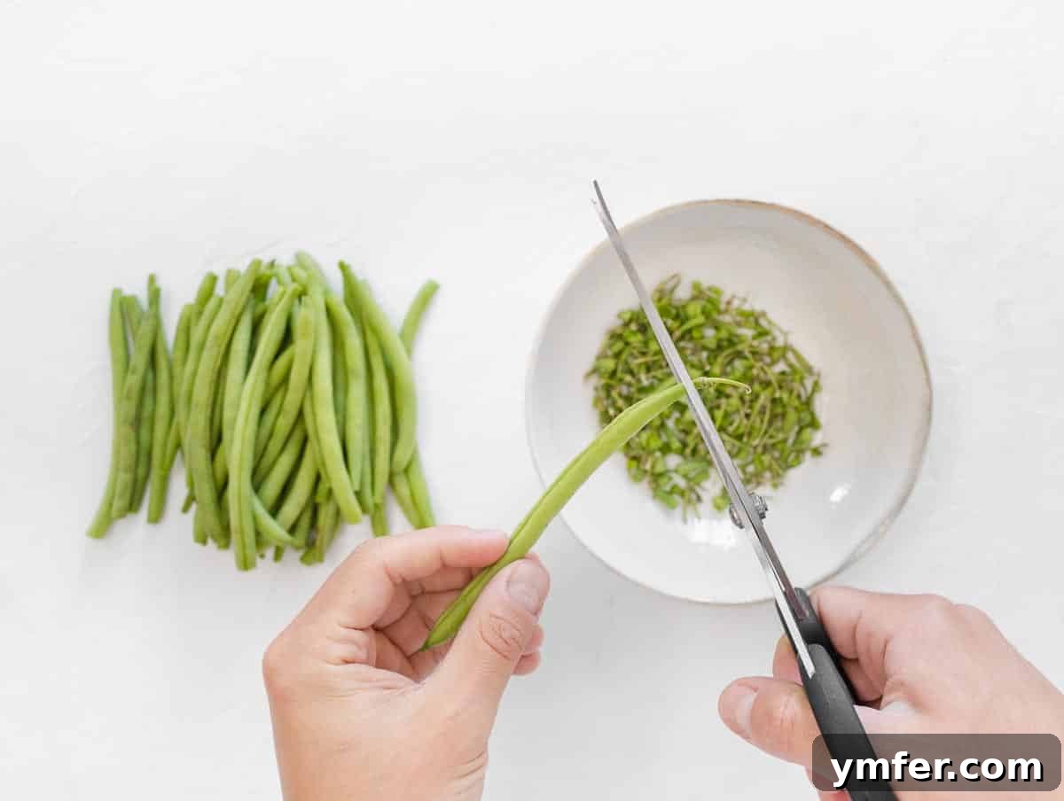 Crispy Air Fryer Green Beans 5 Person trimming green beans using kitchen scissors