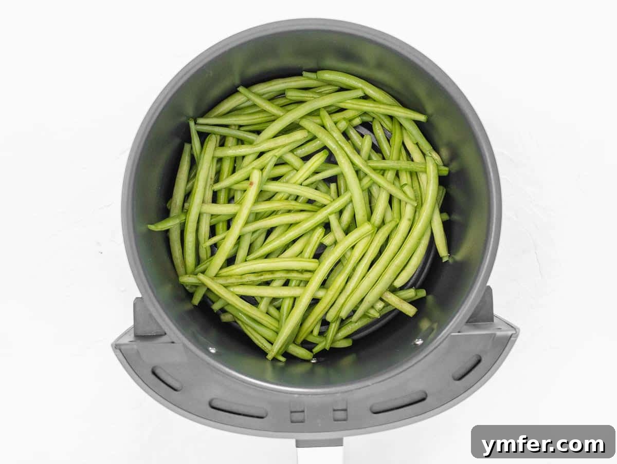Crispy Air Fryer Green Beans 9 Green beans cooking in an air fryer basket, mid-cycle