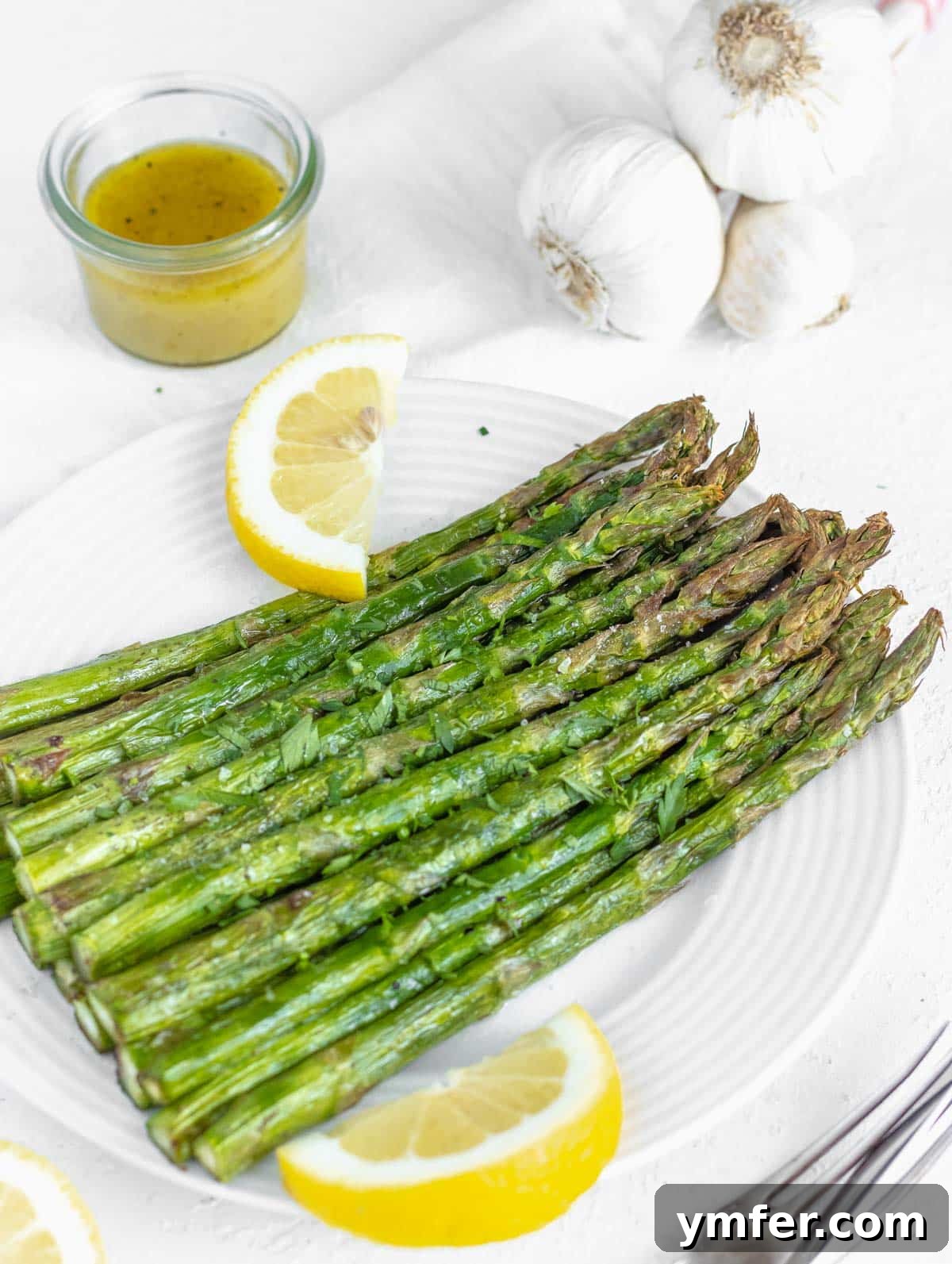 Crispy Air Fryer Asparagus 2 air fryer asparagus on a plate with lemon wedges