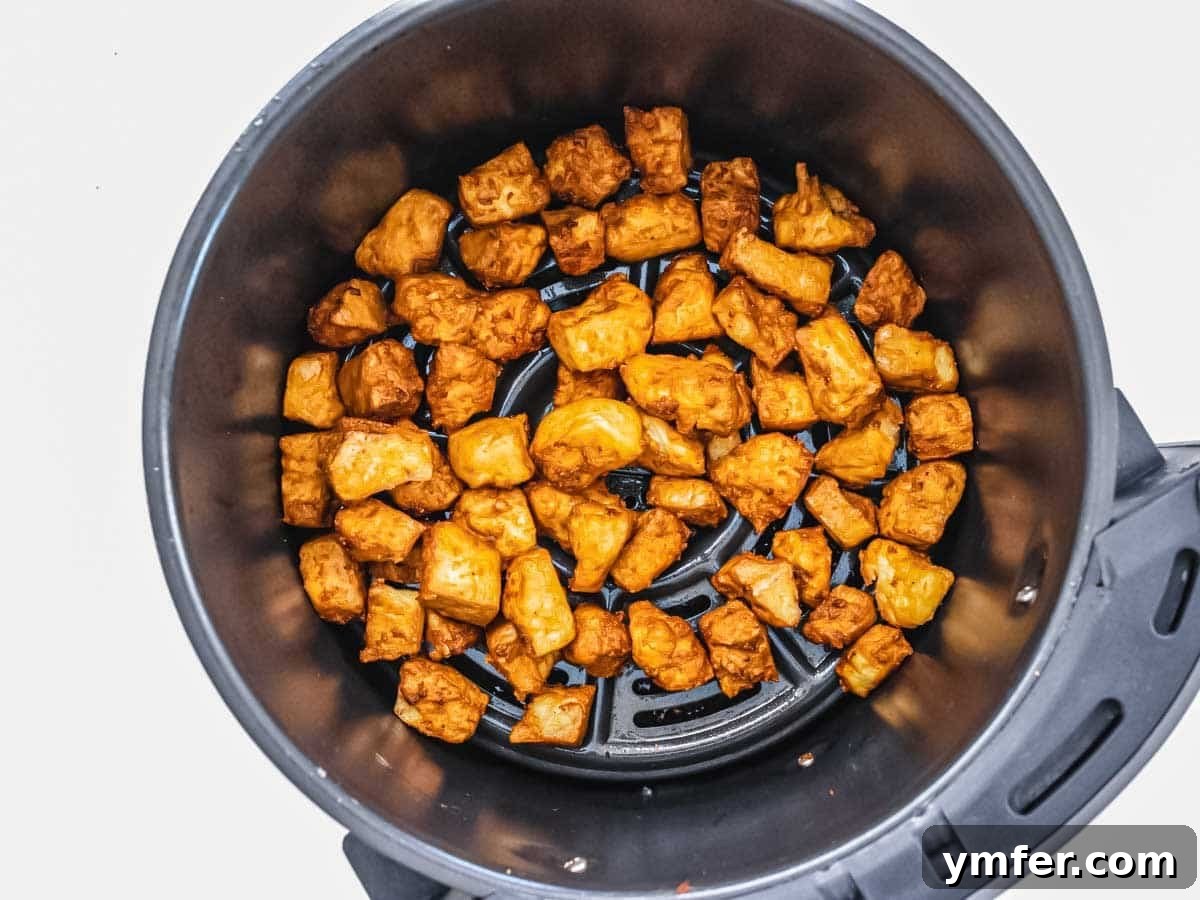 Effortless Crispy Air Fryer Tofu 8 Crispy air fryer tofu, golden brown and cooked, in the air fryer basket.