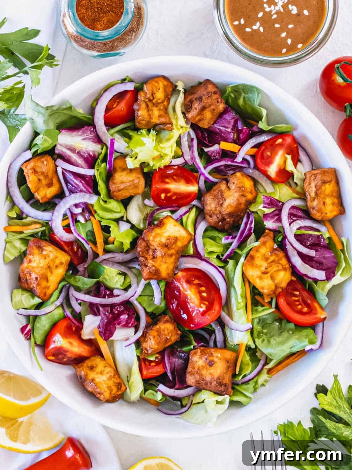 Effortless Crispy Air Fryer Tofu 9 Air fryer tofu served on a fresh green salad with various vegetables.