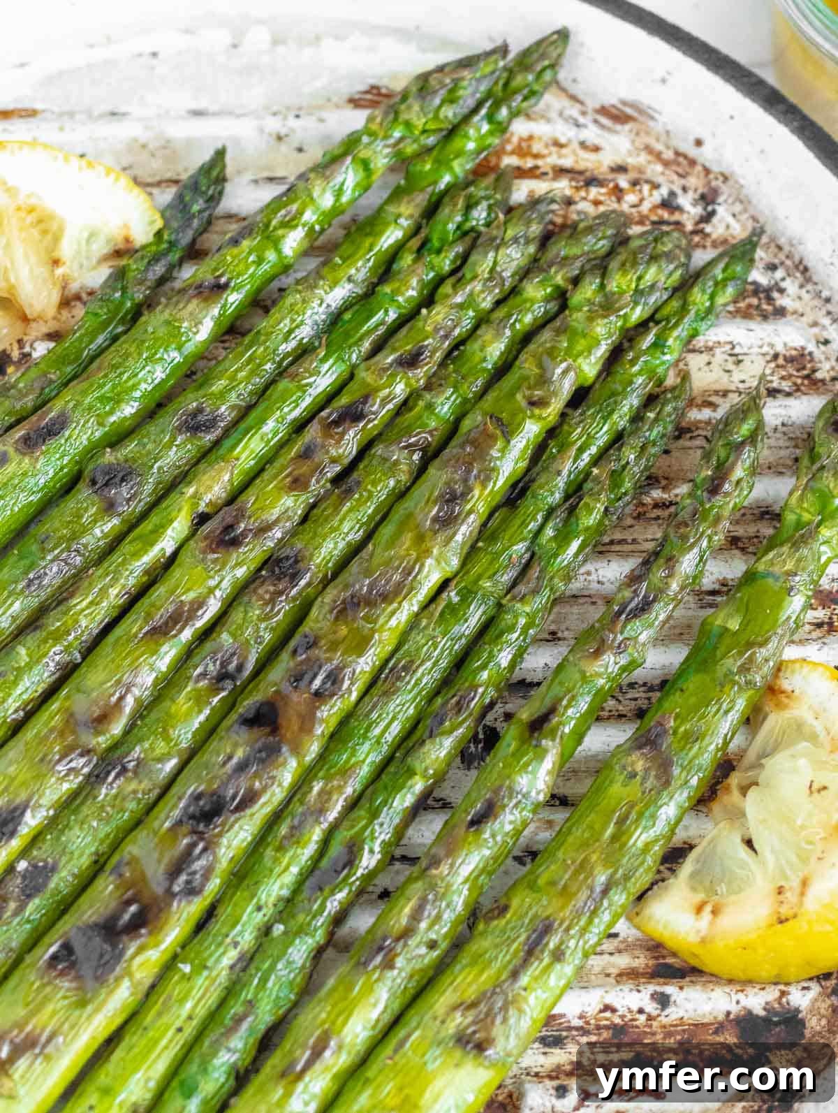 Grilled asparagus cooking on a grill pan, showing early char marks