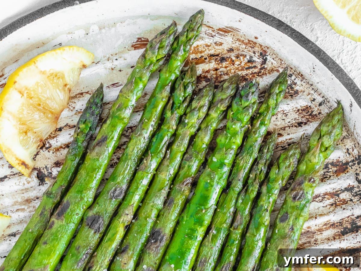 Grilled asparagus on a plate with fresh lemon wedges