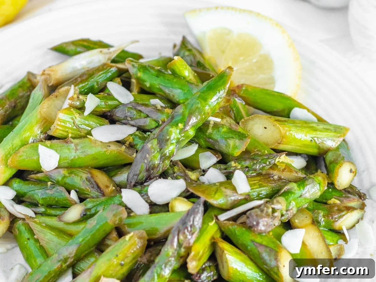 Close-up of perfectly sautéed asparagus spears with a fresh lemon slice.
