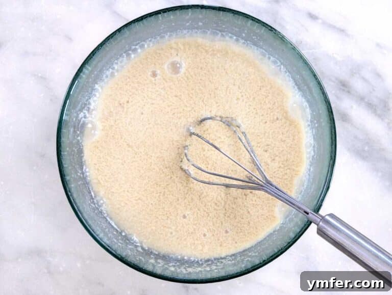Silky Tahini Drizzle 9 whisk in a glass bowl with ingredients for tahini sauce