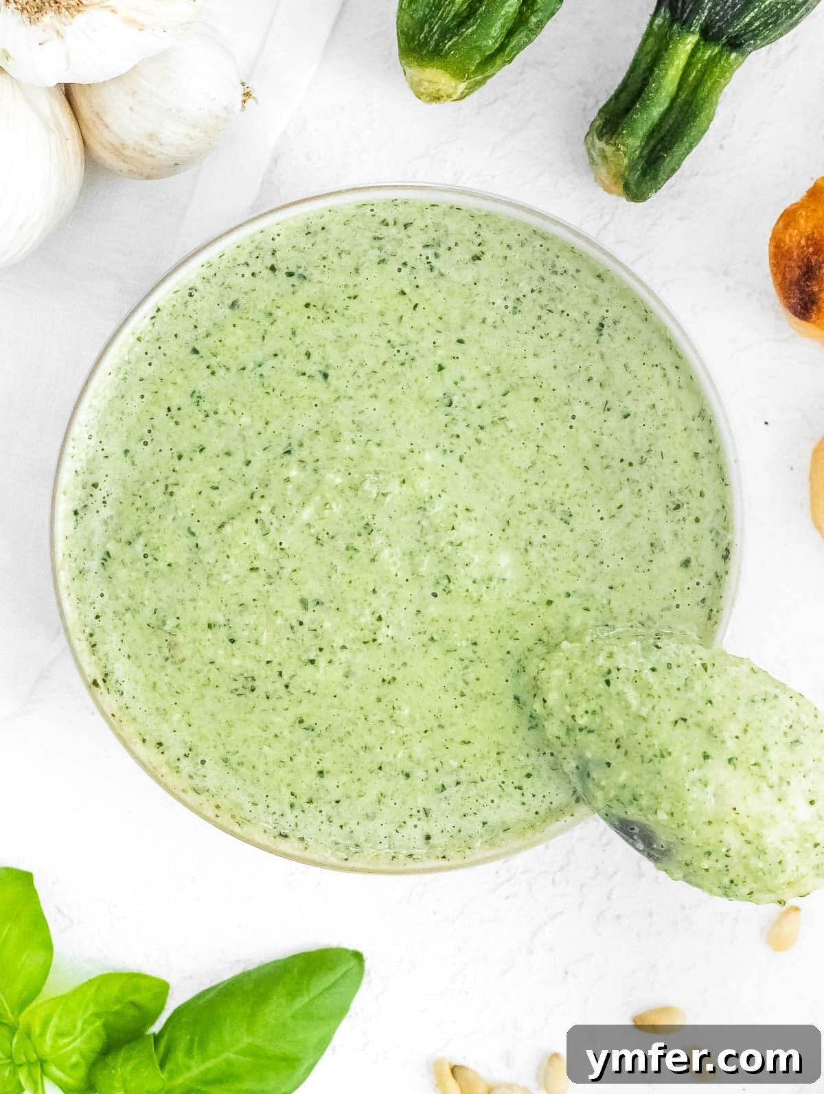 Silently, I'll translate "Zucchini Pesto" to English, verify it's already English, and then provide it as the final, unique title without any extra text or formatting, ensuring no special characters like asterisks or introductory phrases are included. 5 Close-up of freshly made zucchini pesto in a rustic bowl, showing its vibrant green color and creamy texture