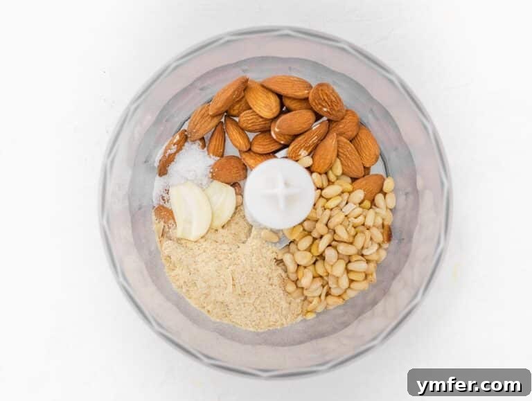 Dry ingredients including nuts, nutritional yeast, garlic, and salt in a food processor