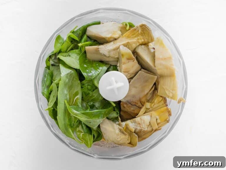 Artichoke hearts, basil leaves, and olive oil added to the food processor