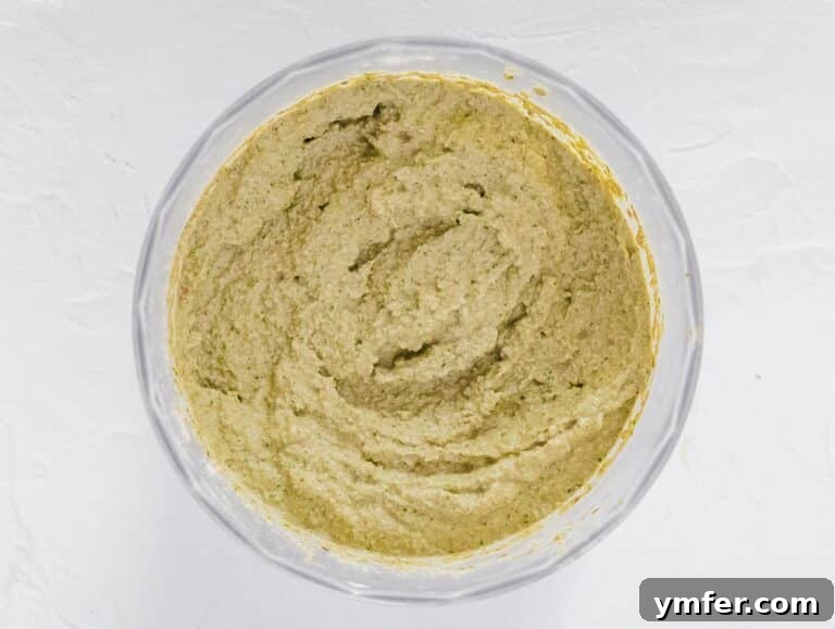 Creamy artichoke pesto being blended in a food processor to achieve desired consistency