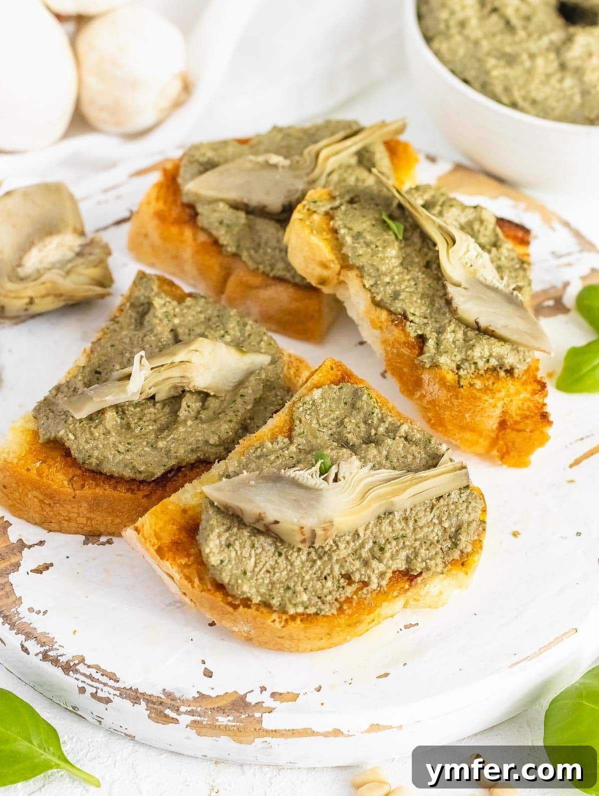 Savory Artichoke Spread 3 Two slices of crispy bruschetta topped with homemade artichoke pesto, garnished with a whole artichoke heart