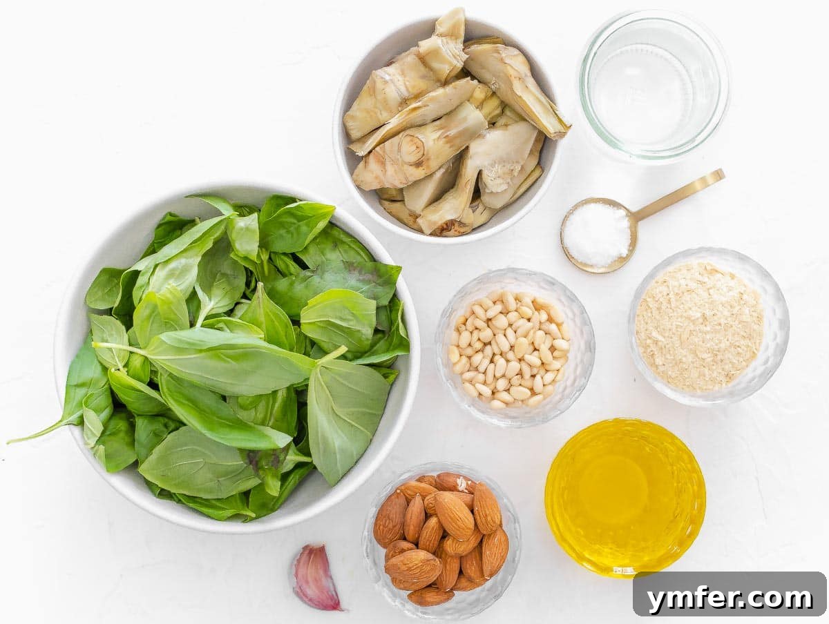 Savory Artichoke Spread 4 Various ingredients laid out for making creamy artichoke pesto: jarred artichokes, fresh basil, pine nuts, almonds, garlic, nutritional yeast, olive oil, and salt