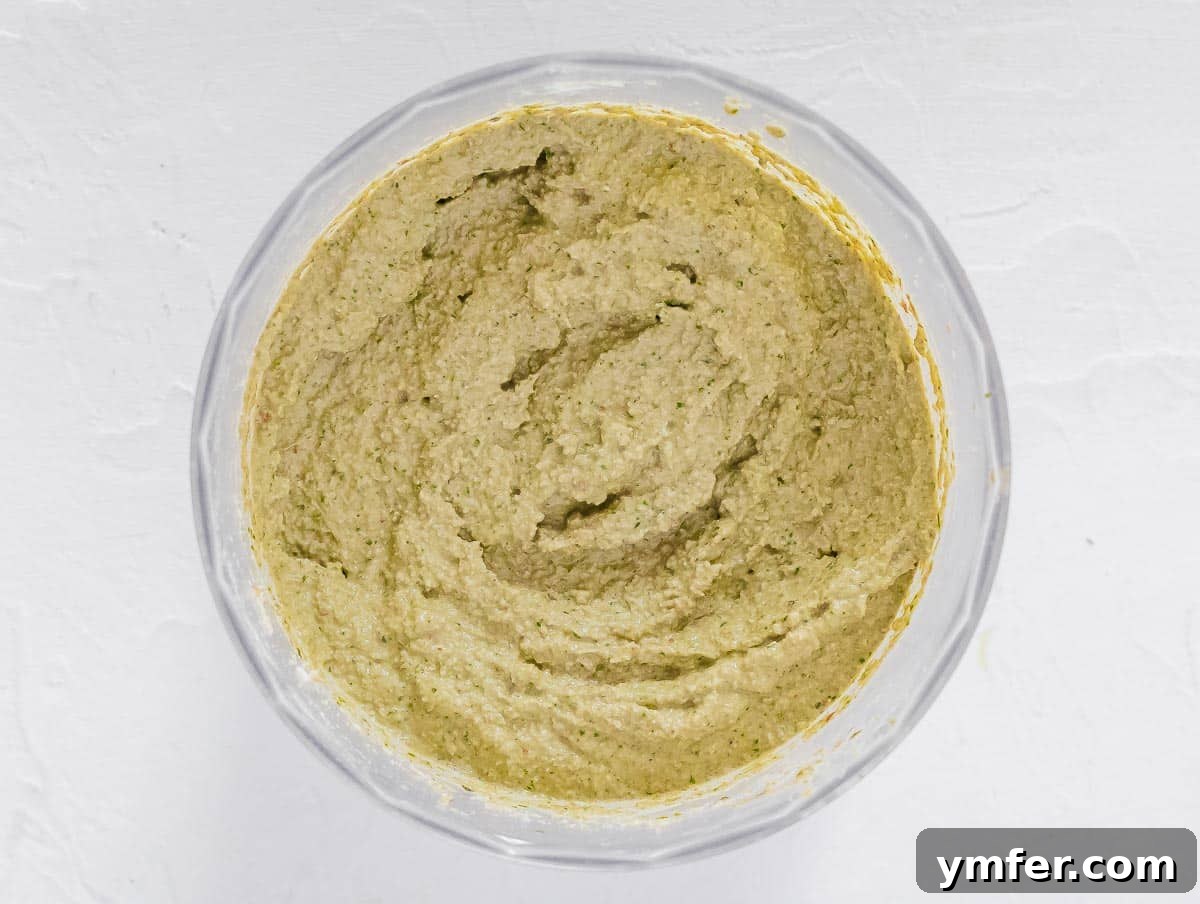 Savory Artichoke Spread 9 Creamy artichoke pesto blending smoothly in a food processor, showing its final vibrant green color