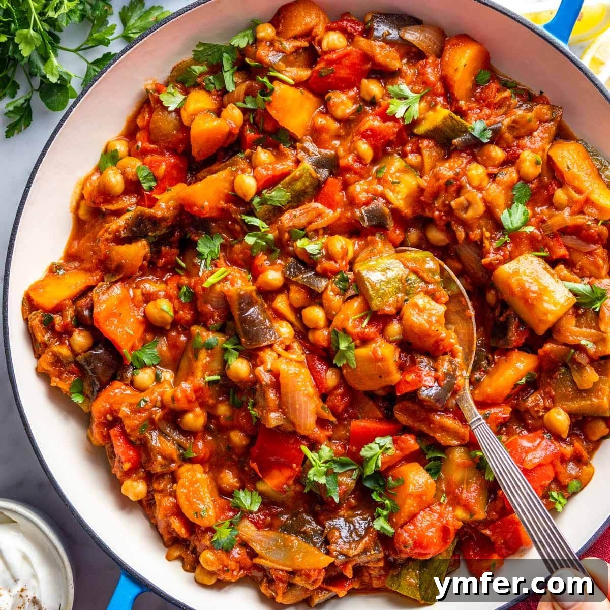 Eggplant Elevated 30 Exciting Recipes 19 Tagine served in a blue skillet with a silver spoon.