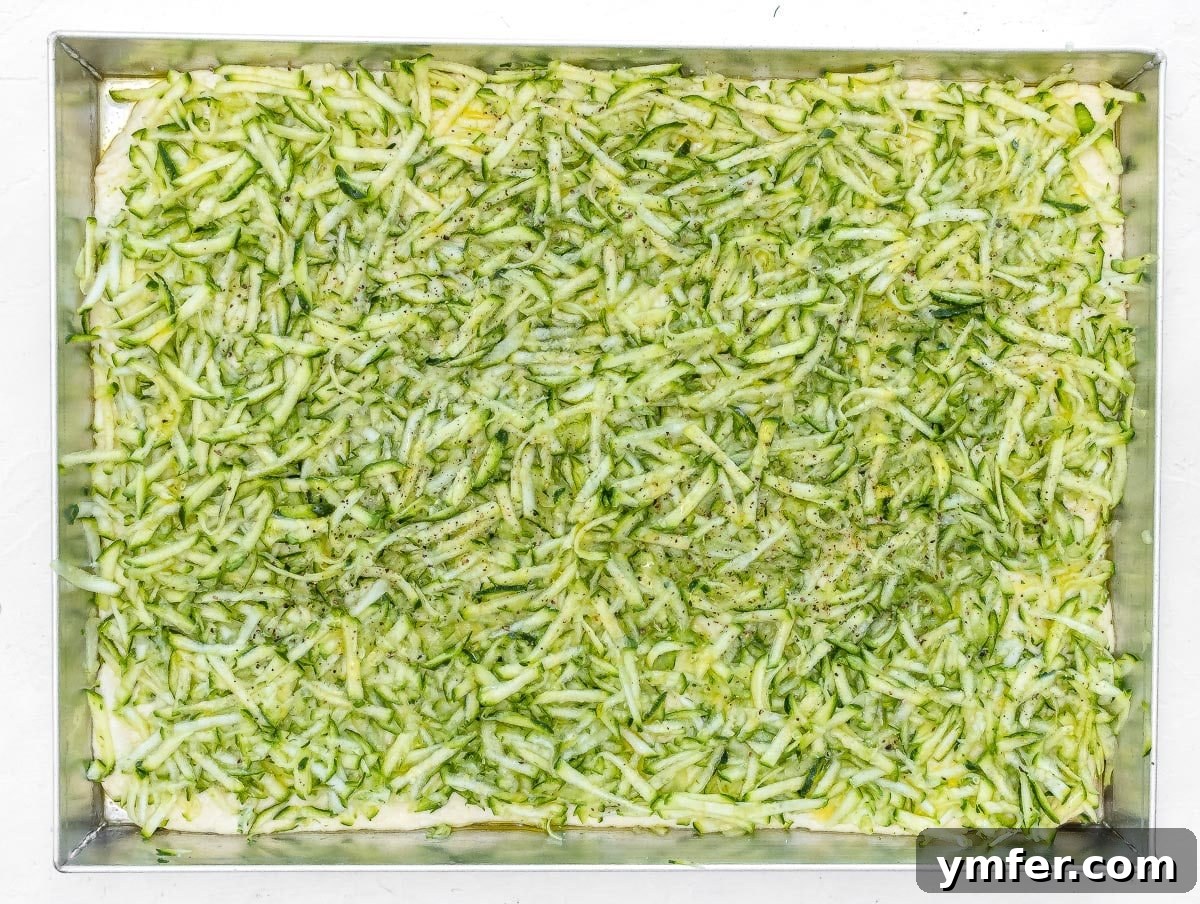Rustic Zucchini Focaccia 13 Close-up of grated zucchini topping seasoned with salt, pepper, and olive oil.