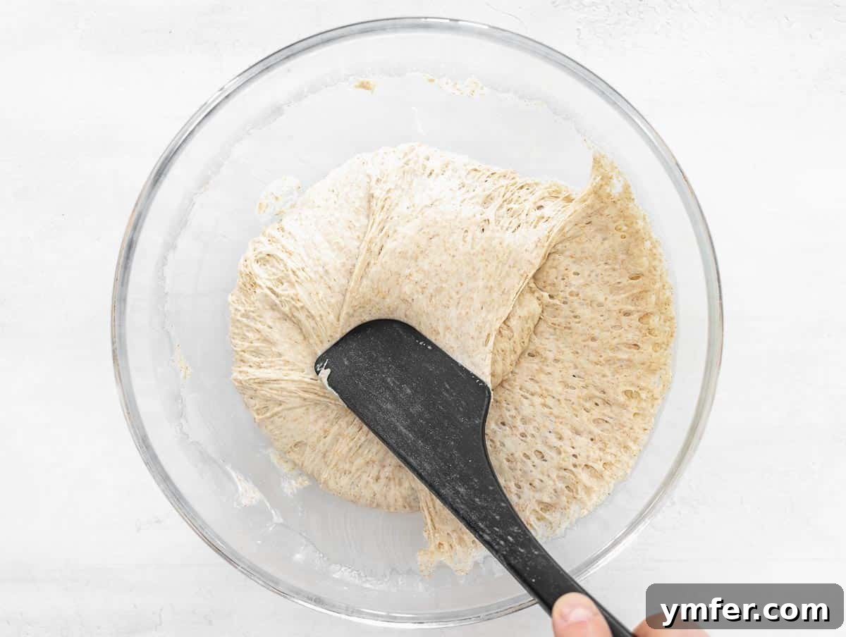 Rustic Zucchini Focaccia 9 A spatula gently folding the proofed focaccia dough in a bowl.
