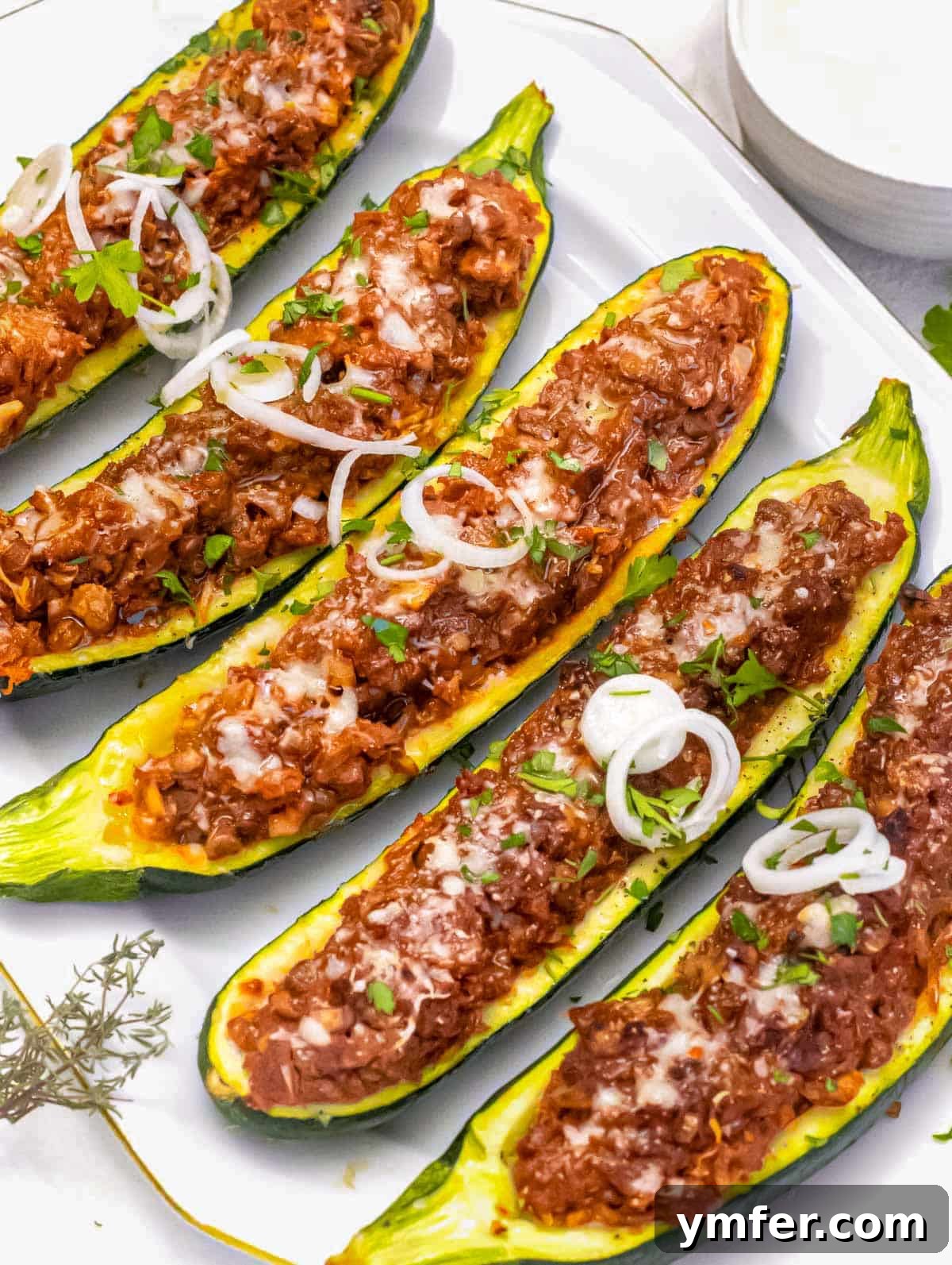 Stuffed Zucchini Canoes 2 Delicious Zucchini boats filled with a savory lentil, tomato, and cheese mixture, ready to be served.
