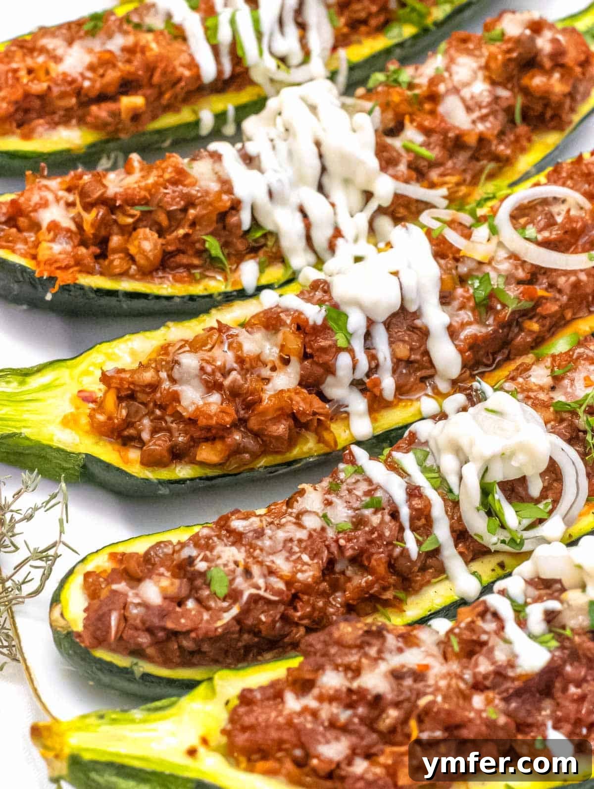 Stuffed Zucchini Canoes 3 Close-up of baked Zucchini boats, garnished with a dollop of sour cream or yogurt, showcasing the rich filling.