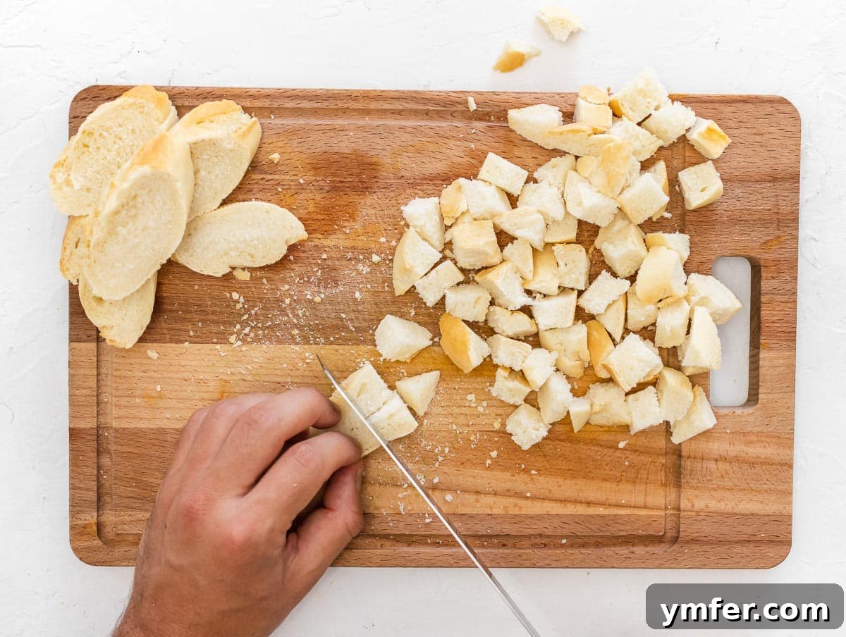 Golden Crunch Air Fryer Croutons 6 cutting a baguette into cubes. A close-up of a baguette being cut into small, even cubes.